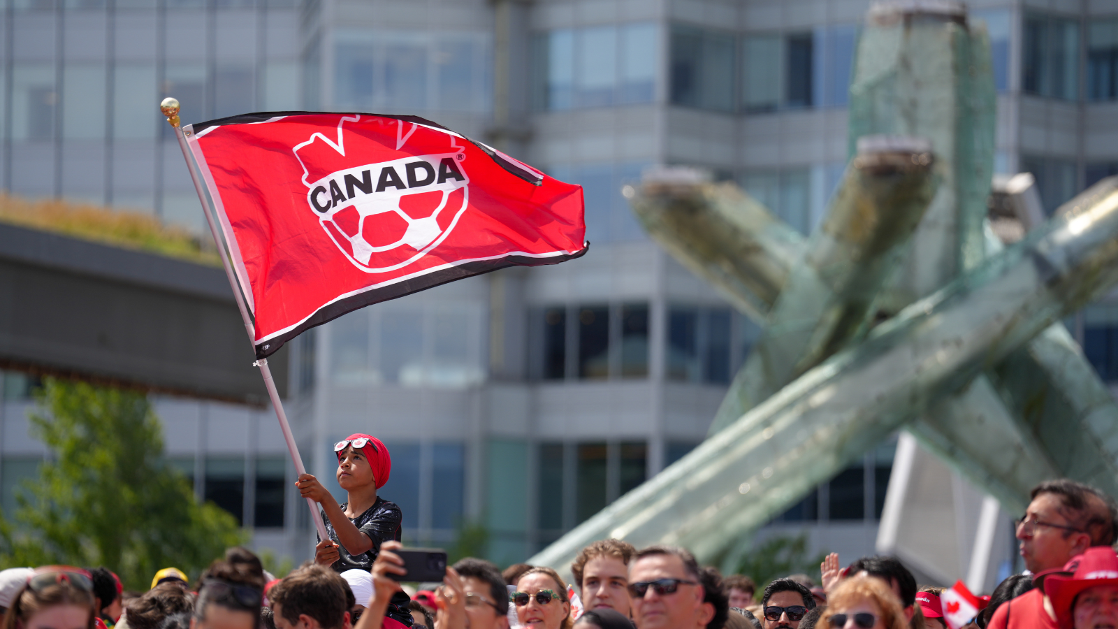 Boy waving Canada soccer flag in crowd